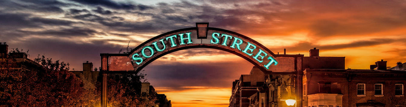 The illuminated South Street arch sign glowing over the street at sunset